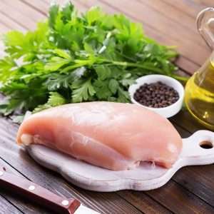 a piece of boneless chicken on a cutting board next to a knife and spices